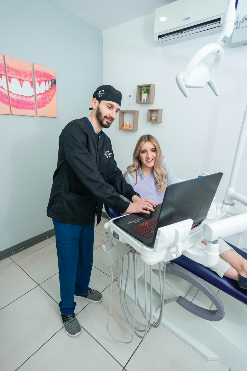 Dentist points to laptop screen explaining treatment to patient.
