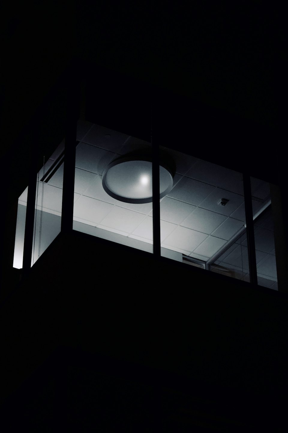 Modern office interior glowing through a large window at night.